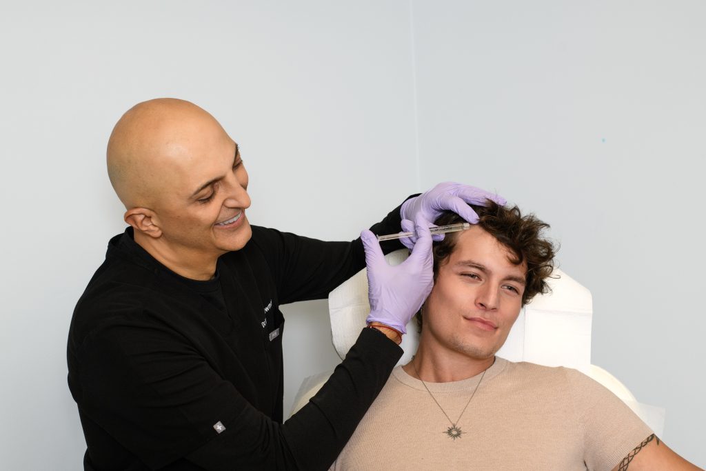 Using a surange, Dr. Nathan Newman is preforming a PRP treatment to young good looking man